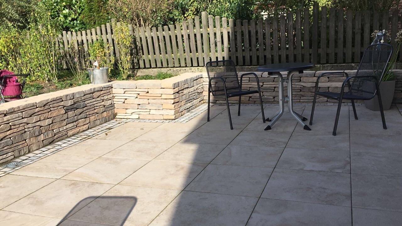 Eine Terrasse mit Steinboden und Natursteinelementen sowie zwei Stühlen und einem Tisch