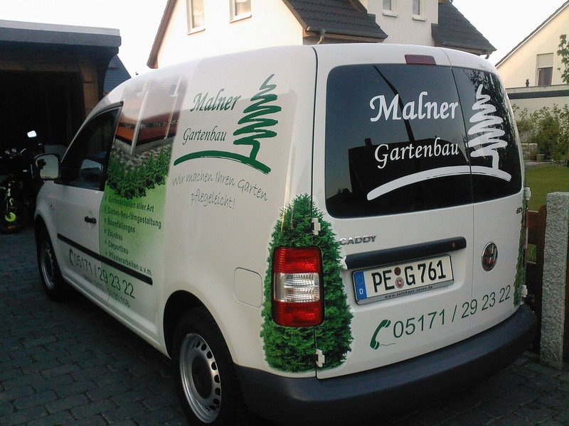 Ein weißer VW Caddy der mit dem Logo und weiteren Elementen von Malner Gartenbau bedruckt wurde