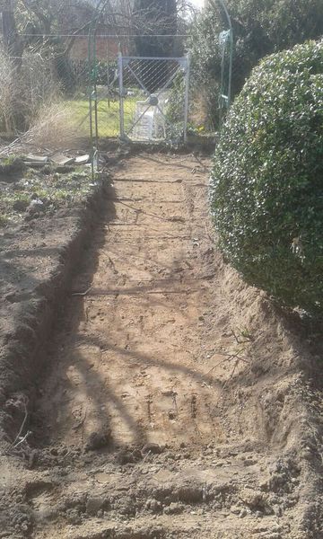 Ein ausgegrabener Weg in einem Garten während Baggerarbeiten